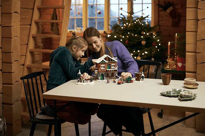 Niño con adulto montando la cabaña de invierno de LEGO ICON
