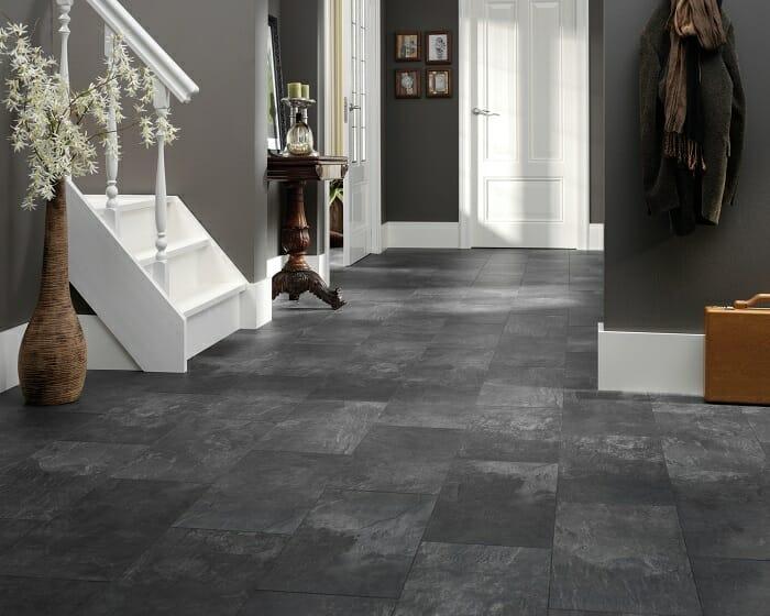 Hall de una casa con baldosas en el suelo de color oscuro estilo piedra