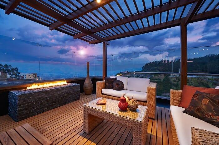 Zona exterior tipo chill out anocheciendo con una pérgola bioclimática de madera