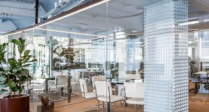 Despacho de Nude Project con planta, sillas blancas y cristalera transparente