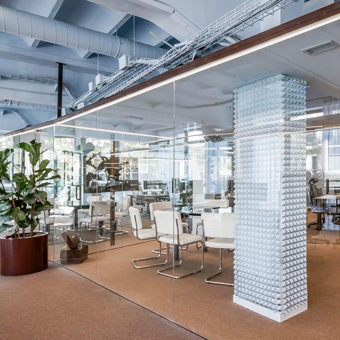 Despacho de Nude Project con planta, sillas blancas y cristalera transparente