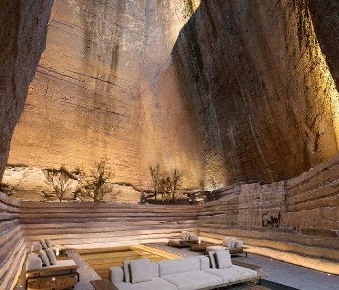 Sofá blanco de exterior y mesas de exterior en el fondo de una montaña iluminada