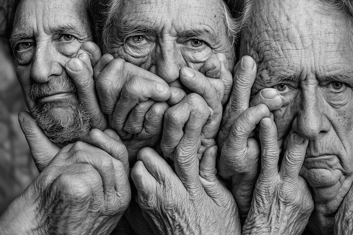 Fotografía en blanco y negro del rostro de personas mayores y sus manos