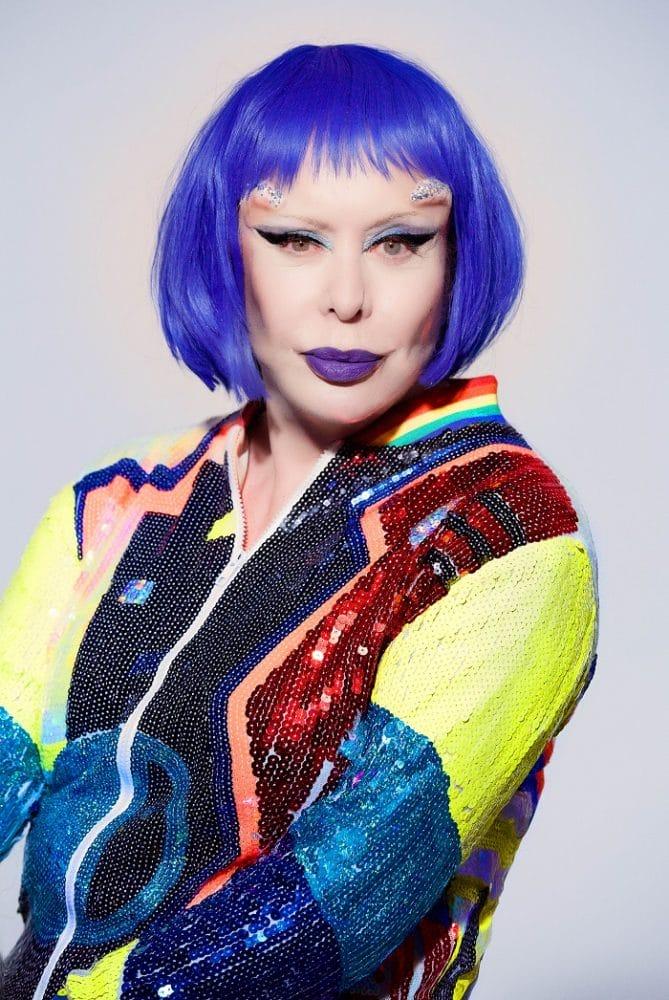 Fotografía de ORLAN con cazadora moderna y colorida con el pelo azul y los labios morados
