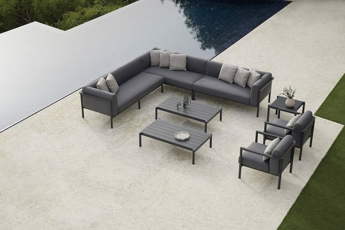 Gran sofá con sillones y sillas de exterior al lado de una piscina