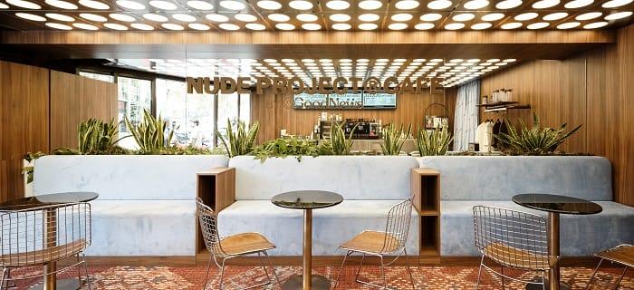 Zona de sofás azules y mesas redondas en cafetería Nude Project