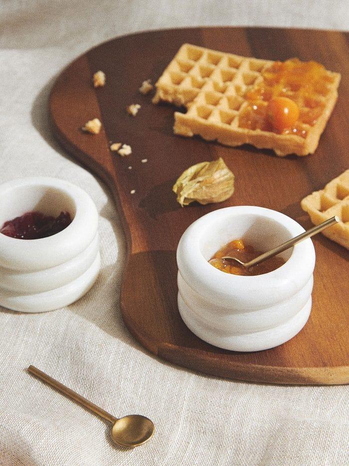 Mesa con una bandeja y unos cuencos de mármol de westwing con miel