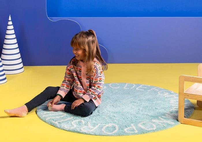 Niña sentada sobre alfombra redonda Aldi