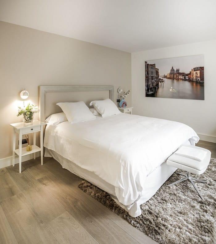 Dormitorio con cama con cabecero blanco y mesillas blancas