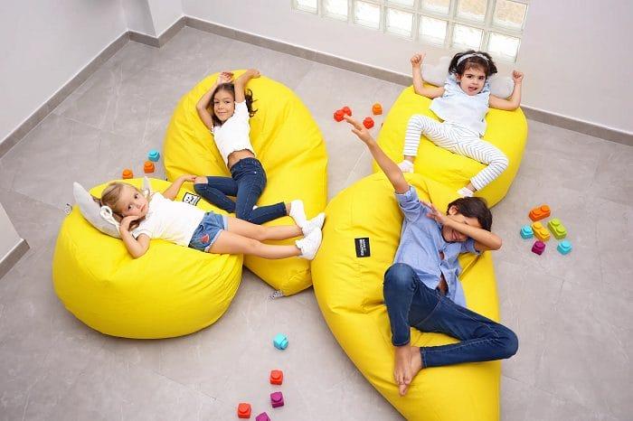 Grupo de niños disfrutando con varios puffs amarillos