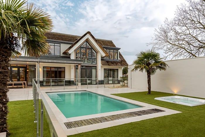 Fachada de la casa de la modelo Romee con piscina y cesped