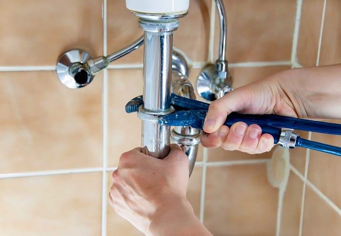 Mano apretando una tubería de fregadero