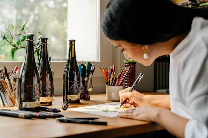 Fotografía de la ilustradora Ana Jarén dibujando los manteles de colaboración con Cervezas Alhambra