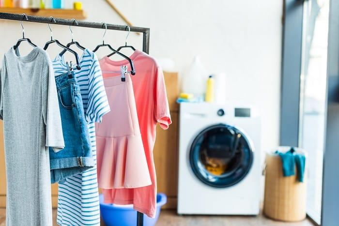 Ropa en percha limpia y al lado una lavadora