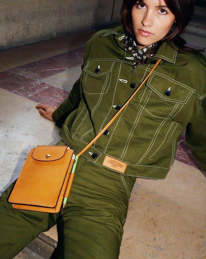 Modelo con ropa vaquera verde y bolso marrón Longchamp tipo banderola
