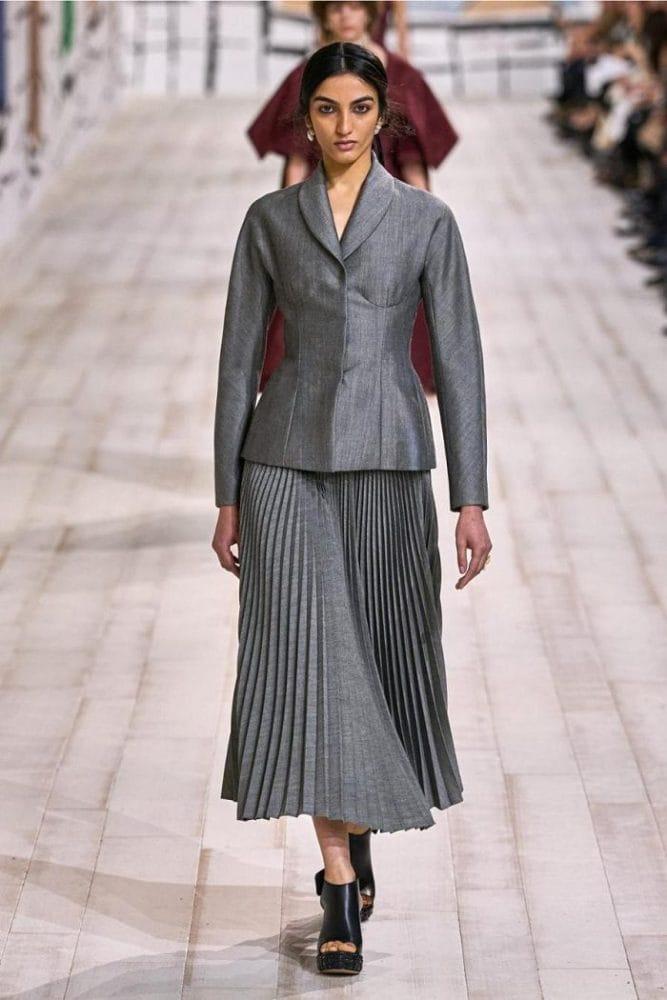 Modelo con un traje de chaqueta y falda gris y zuecos negros