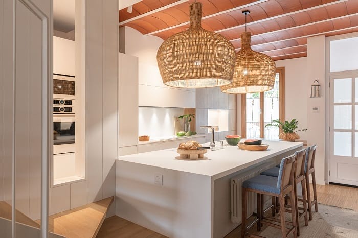 Cocina con una mesa con sillas con unas lámparas colgantes encima