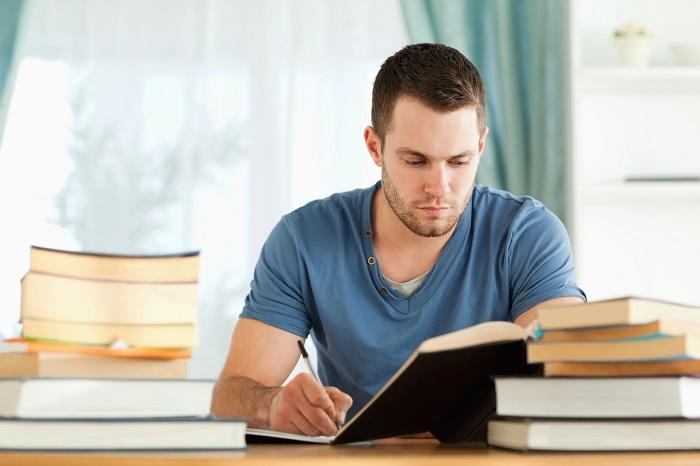 Hombre estudiando con varios libros sobre la mesa