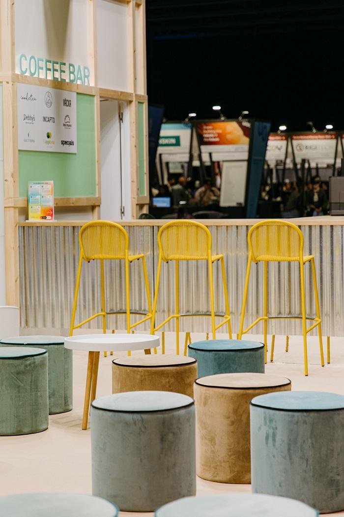 Taburetes amarillos y puf en feria de diseño de stands