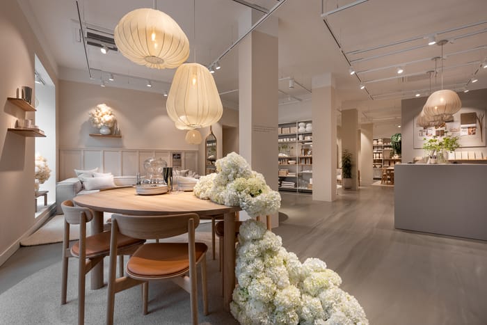 mesa de madera decorada con rosas blancas de la nueva tienda de Bolia