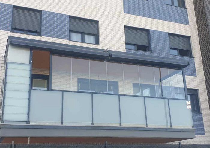 Fachada de unos pisos con terraza con cortinas y cerramientos de cristal