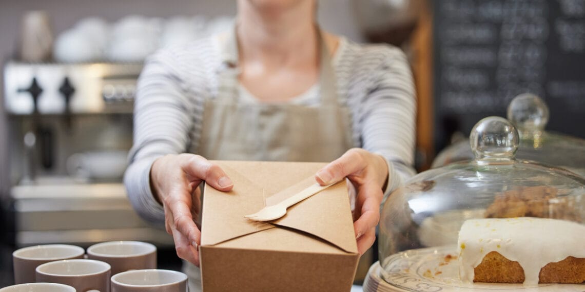 modelo ofreciendo una caja con producto en una cafetería