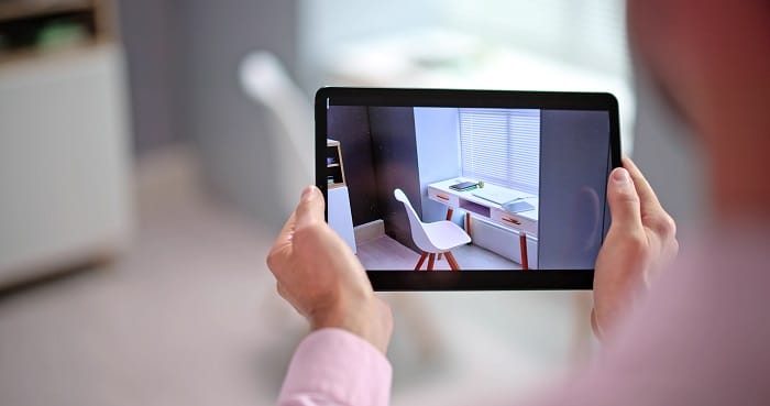 Persona sujetando una tablet con realidad aumentada en decoración de su salón