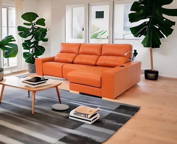 Sofá chaise longue color naranja en un salón con plantas y alfombra