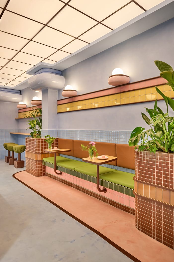 art deco en Amiko Gelato en Barcelona sofás verdes con mesas rosas y plantas decorativas