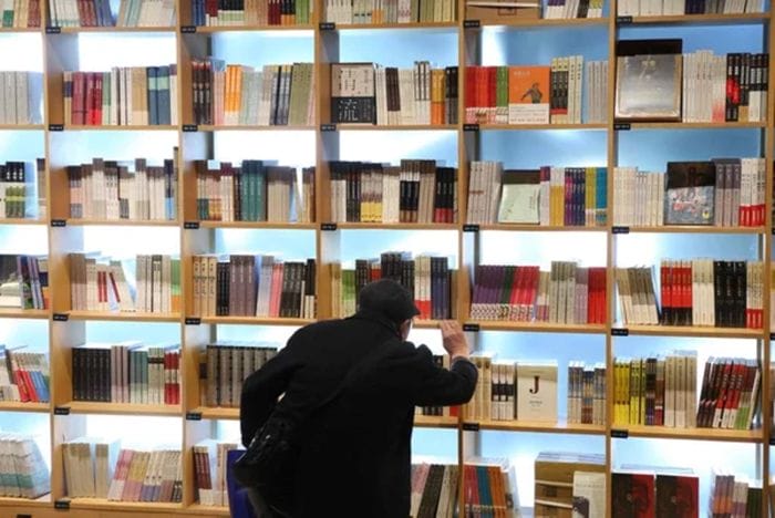 joven buscando libro en una biblioteca de segunda mano