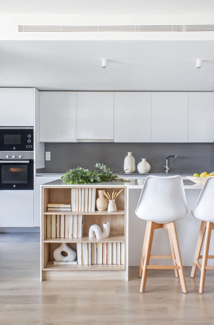 Cocina de estilo minimalista en un piso de Valencia, diseño de Anabel Soria, con muebles blancos y detalles en acero inoxidable