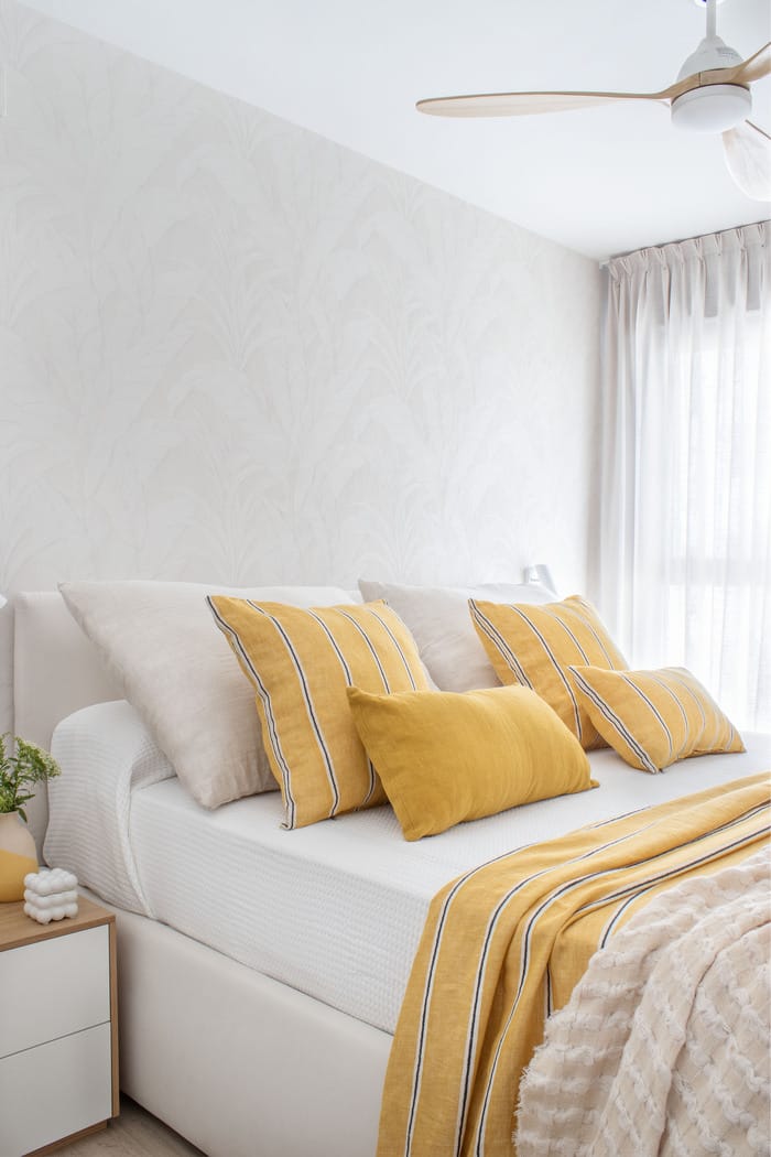 Dormitorio principal en piso valenciano, rediseñado por Anabel Soria, con cama de estilo moderno, textiles suaves y decoración cálida con tonos neutros y amarillos