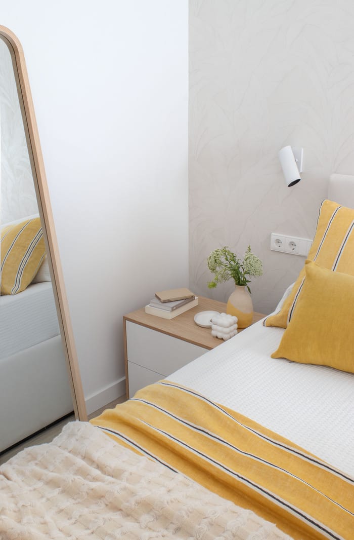Espejo decorativo en el dormitorio de un piso valenciano, diseño de interiores de Anabel Soria que añade profundidad al espacio.