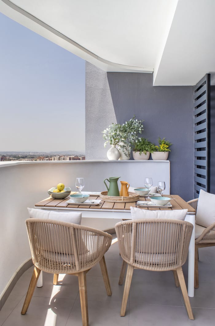 Terraza de piso valenciano, rediseñada por Anabel Soria, con mobiliario de exterior moderno y vistas panorámicas de la ciudad