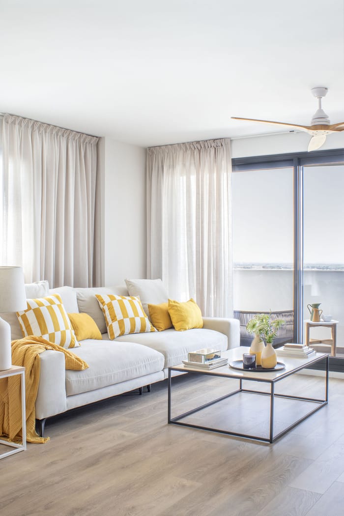 Sala de estar renovada en un piso valenciano, diseñada por Anabel Soria, con tonos neutros, mobiliario moderno y detalles decorativos elegantes