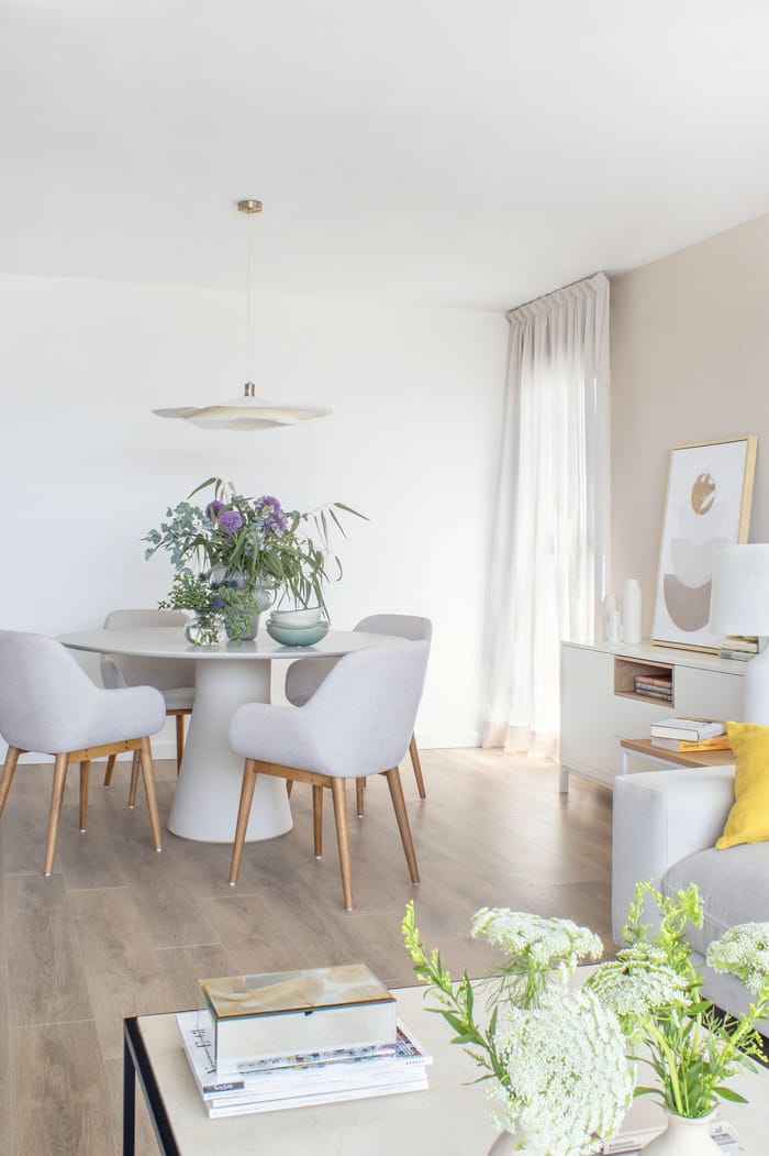 Comedor transformado en un piso valenciano por Anabel Soria, con mesa de madera blanco, sillas contemporáneas y lámpara colgante de diseño