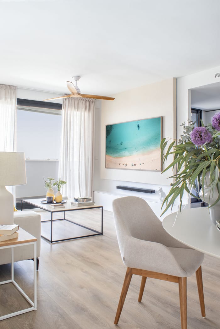 salón rediseñada de un piso en Valencia, con detalles decorativos naturales y cuadro de arena y mar diseñados por Anabel Soria