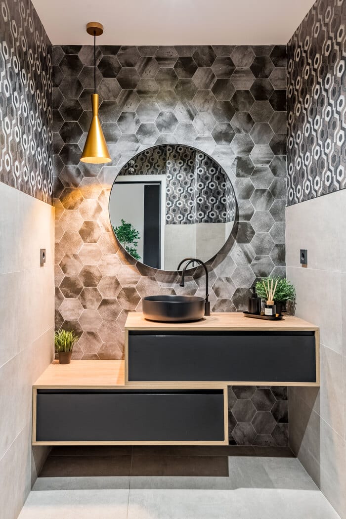 baño con espejo redondo decorado con plantas y mobiliario negro