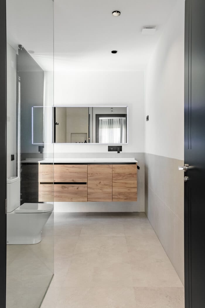 Baño de estilo minimalista con lavabos volados y grifería en negro mate, diseño de ALEM Arquitectura