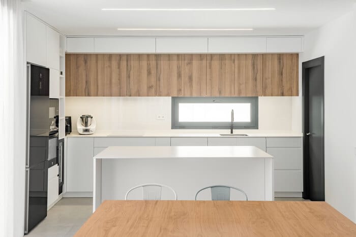 Cocina de concepto abierto con isla en blanco y muebles integrados, estilo minimalista en proyecto de ALEM Arquitectura