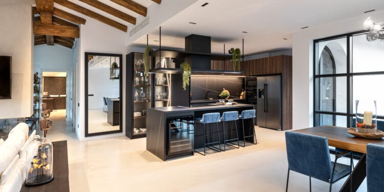 Imagen panorámica de la cocina con mobiliario negro y detalles en madera