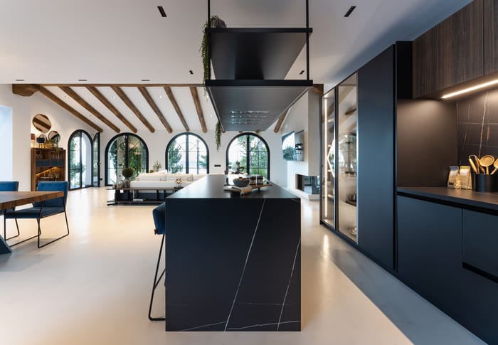 Cuatro ventanales que inundan de luz natural la cocina, destacando su equilibrio entre tonos oscuros y luminosidad.