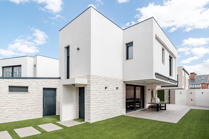 fachada con voladizo de piedra y pequeño jardín de entrada