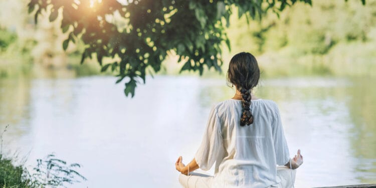 Mujer meditando frente a la laguna