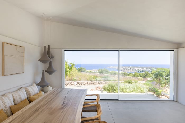 Espacios interiores minimalistas en una casa de Menorca, decorados con tonos neutros, tejidos de lino y detalles que evocan la serenidad mediterránea