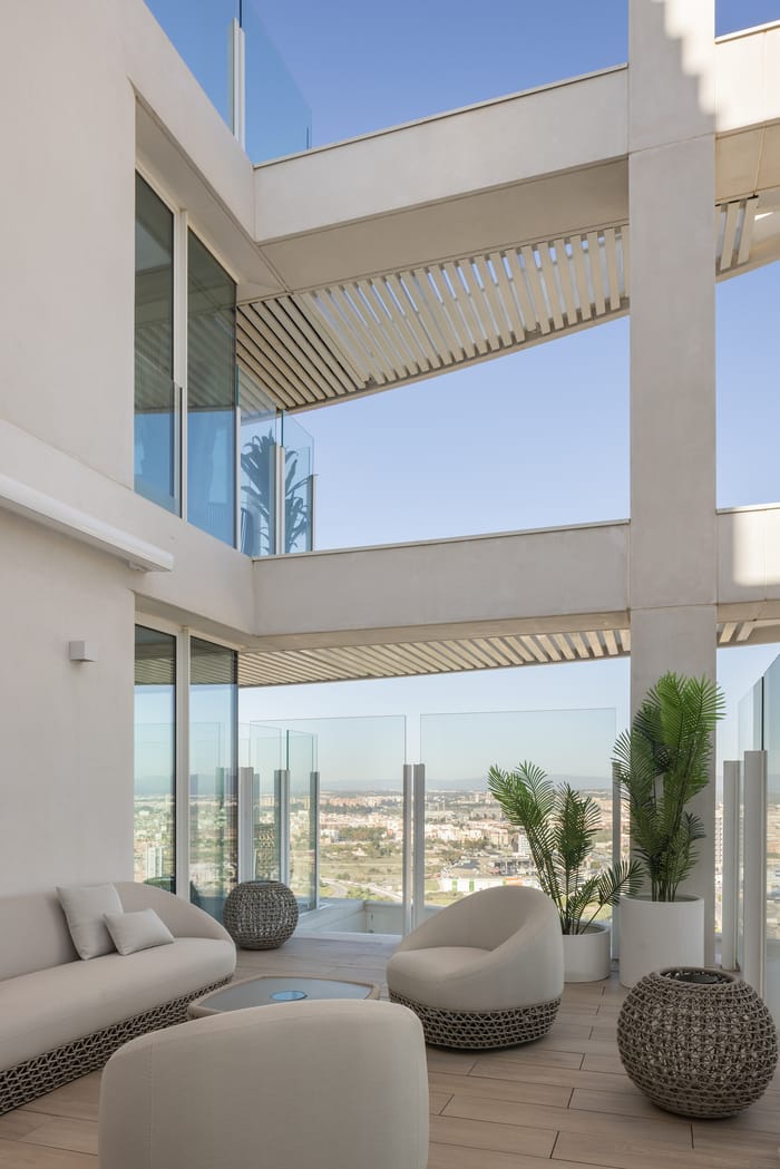 Terraza privada en la Torre IKON de Valencia, con suelo de tarima exterior, mobiliario de diseño contemporáneo y vistas despejadas a la ciudad y al horizonte