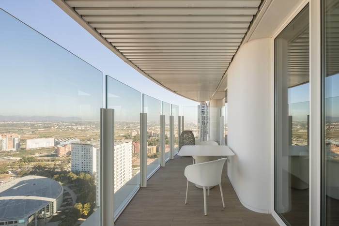 Zona de estar luminosa en un apartamento de la Torre IKON, Valencia, con ventanales del piso al techo que ofrecen vistas panorámicas