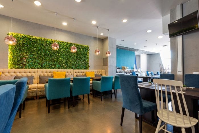 Interior de una cafetería de Hotel con jardín vertical y sillones de terciopelo. Tendencias de muebles para restaurantes