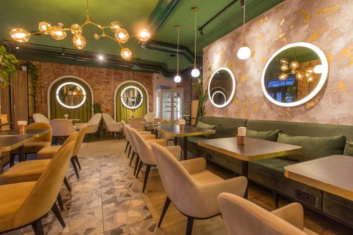 Muebles para restaurantes. Interior de un restaurante con decoración de sillas en beige y paredes beige y verde. Iluminación de techo de de diseño