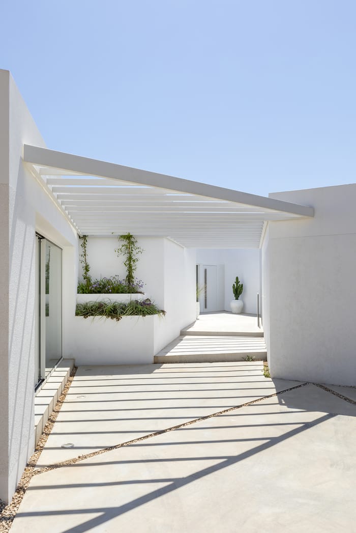 Vista exterior de una casa de Menorca, con líneas simples, colores neutros y un diseño que respeta el entorno natural del Mediterráneo